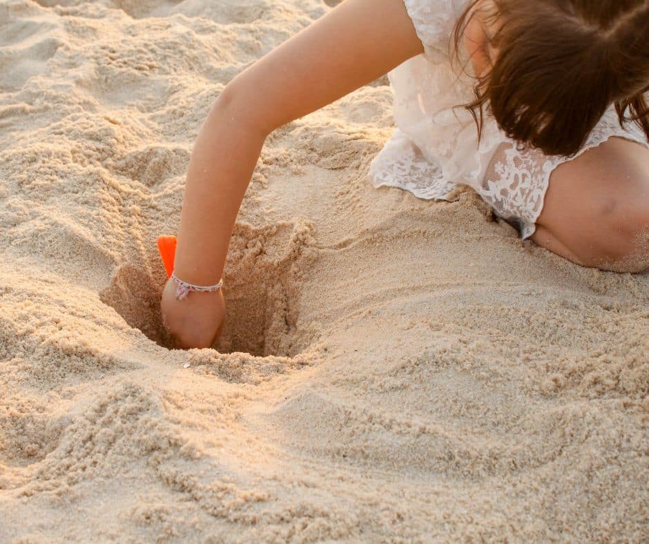 Djevojčica se bezbrižno igra u pijesku na plaži, podsjetnik na važnost bezbrižnog ljetovanja uz savjete Poliklinike Smile