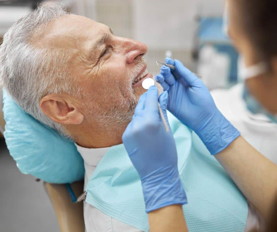 Stomatolog vrši pregled zubiju starijeg pacijenta u modernoj stomatološkoj ordinaciji - zubni implantati